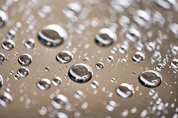 Water beading on a shiny black car hood